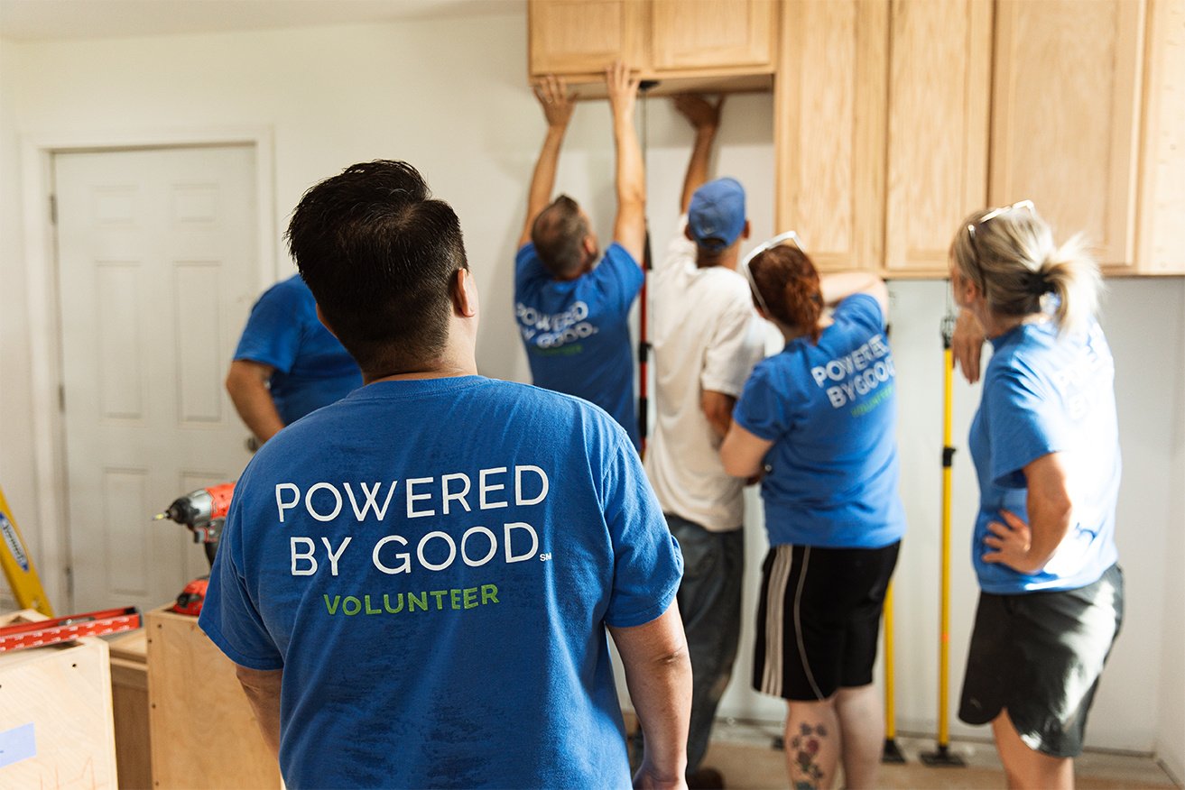 Lake Trust team member building a kitchen in a Powered by Good shirt.