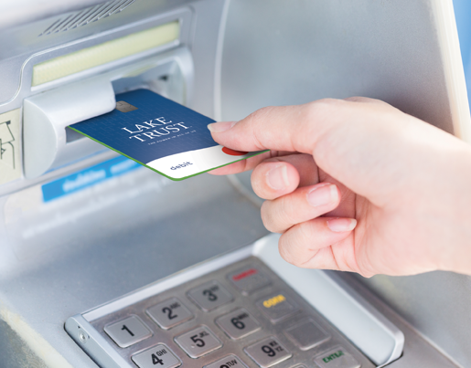 A person inserts a Lake Trust debit card into a video teller machine