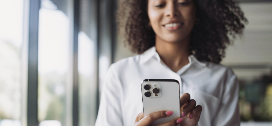 A woman in a white shirt texts on a phone