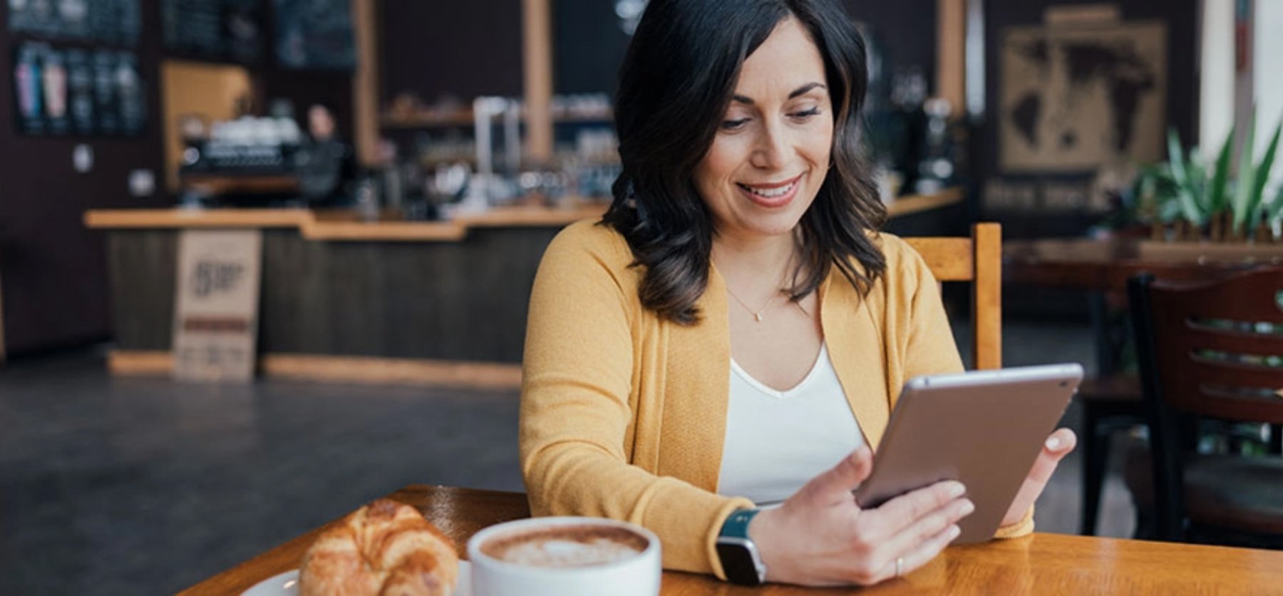 Woman at cafe working on tablet device. 