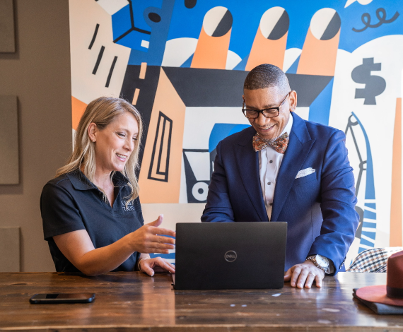 Man and woman smiling while looking at a computer