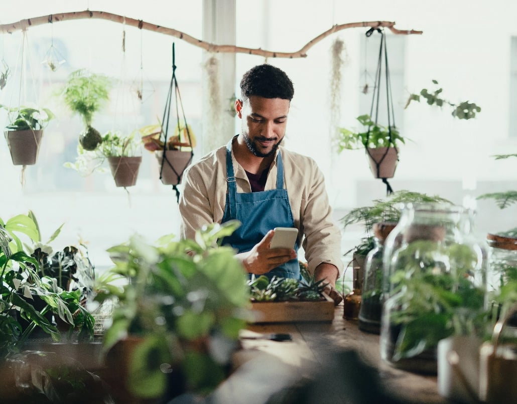 Team member in plant store on his cell phone.