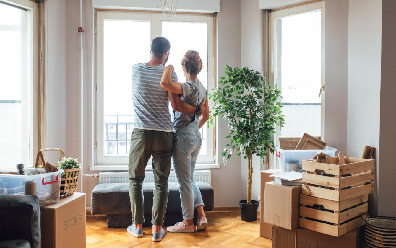 a man and woman looking out the window of their new home