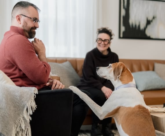 Michael, a Lake Trust member, holds up a treat as a brown and white dog places a paw on Michael's leg