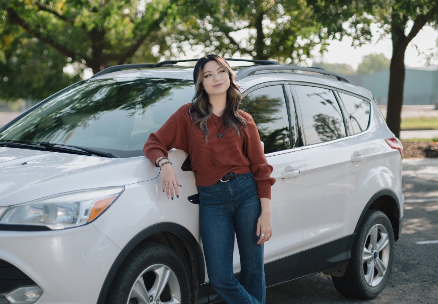 Kadence, a Lake Trust member, stands in front of a white SUV