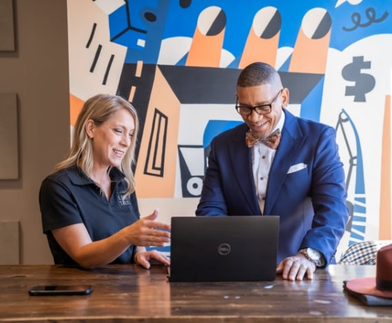 Ne'Gyle, owner of Bleu Bowtique, looks at a computer screen with a Lake Trust team member