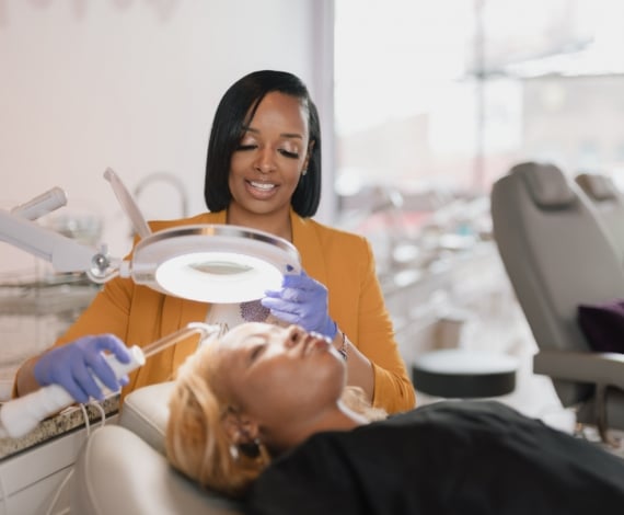 Jessie helping a customer lying in a chair at skinphorea